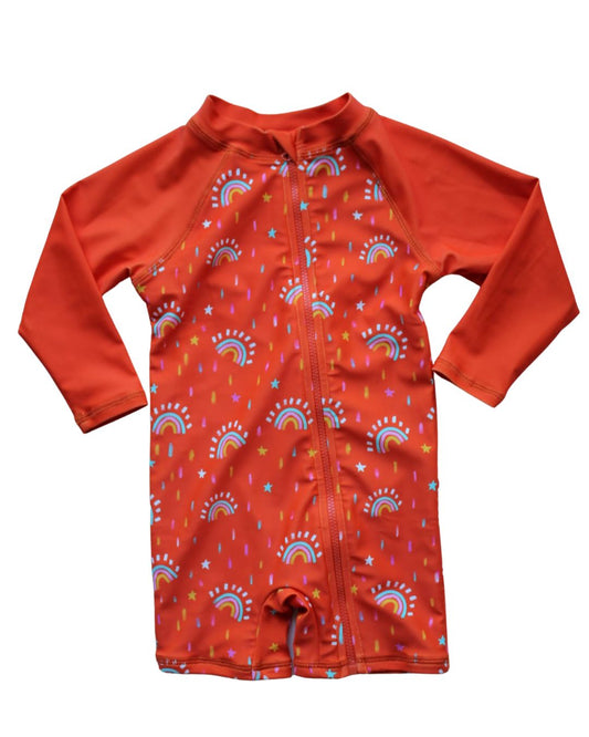 A long-sleeve baby swim shirt in a vibrant orange-red color, featuring a full front zipper and an all-over print of rainbows, stars, and sprinkles in blue, yellow, and white.